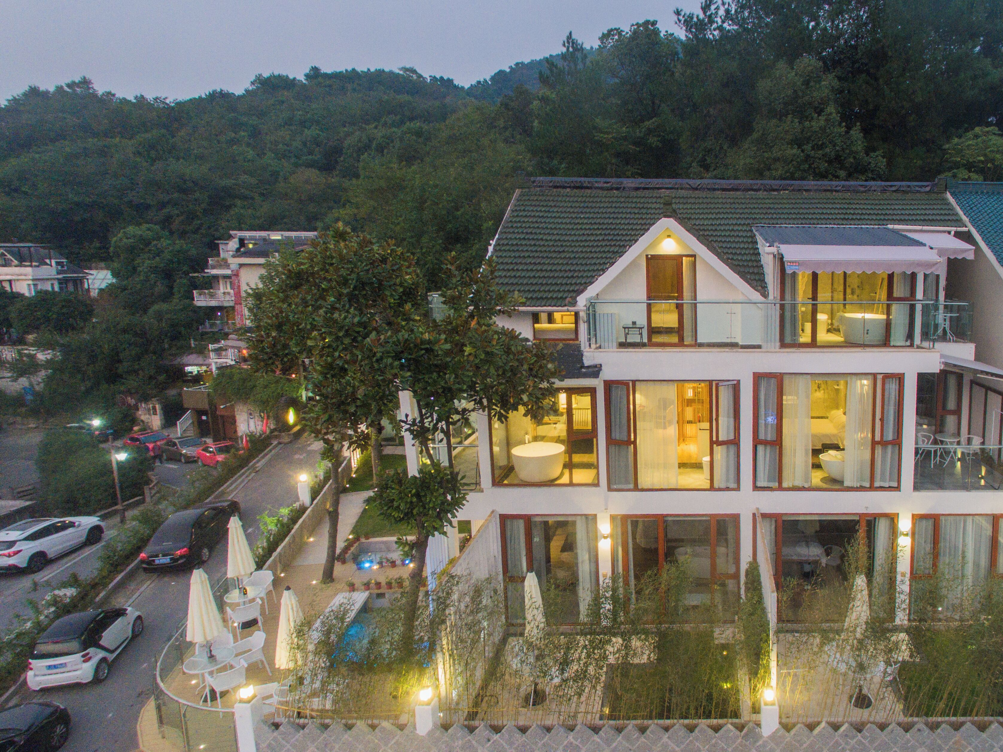 A two-story building with a balcony, a swimming pool, and a garden area.