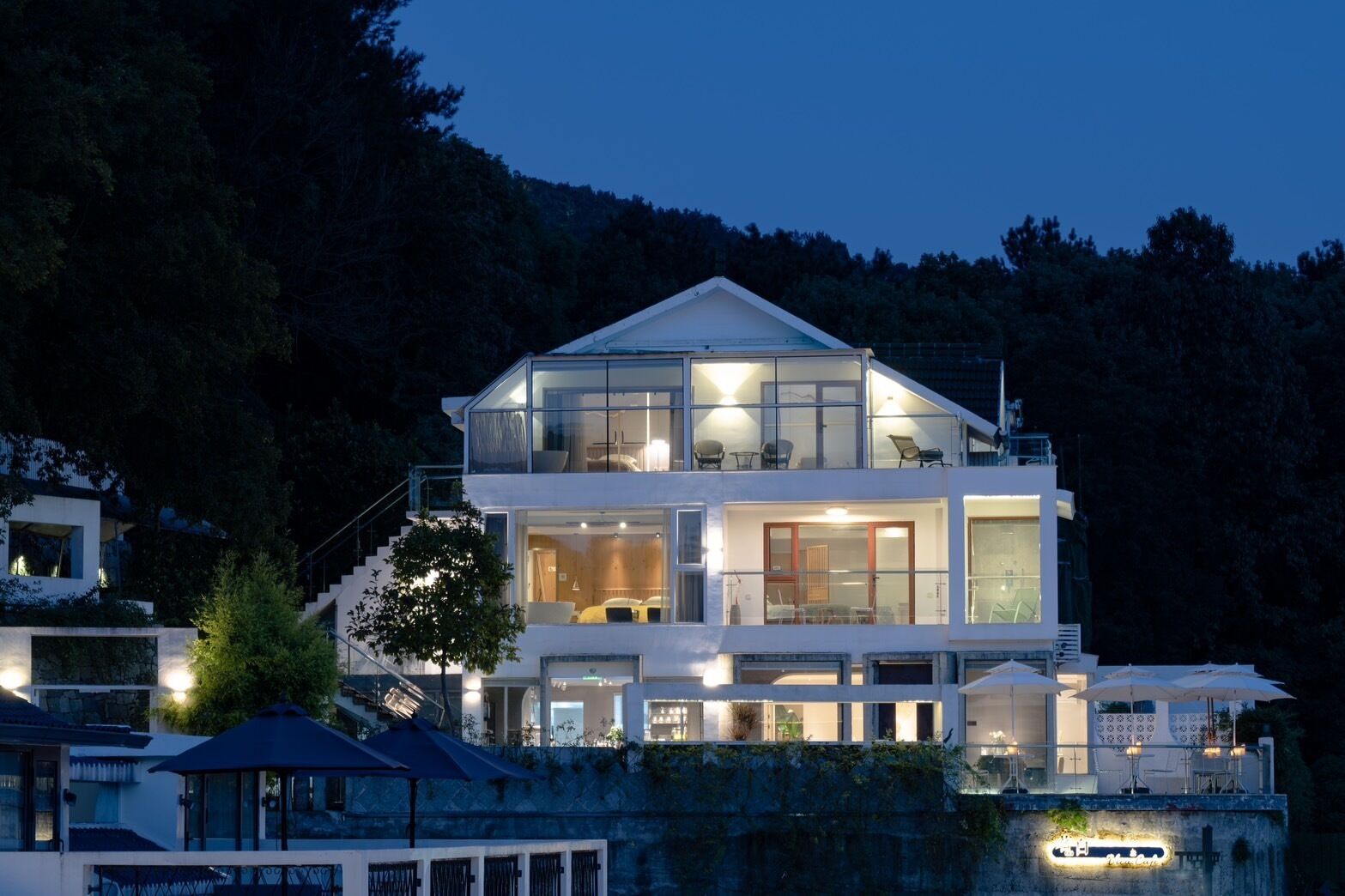 A modern two-story house with large windows and a balcony.
