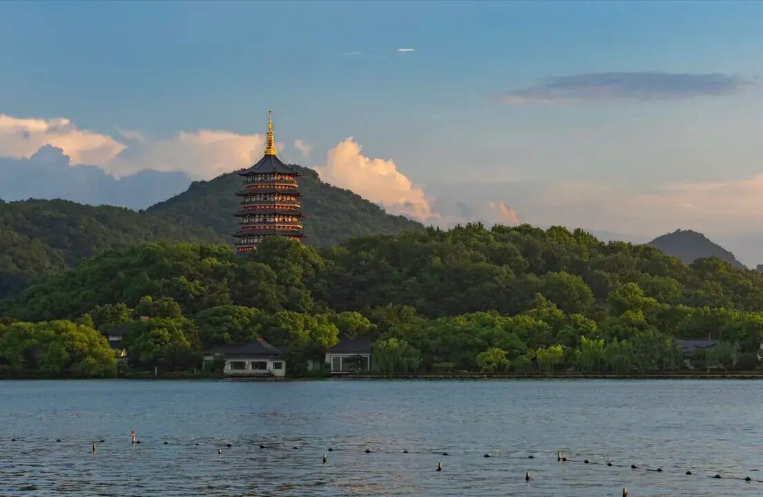 A pagoda-style tower with multiple tiers, surrounded by lush greenery and a body of water.