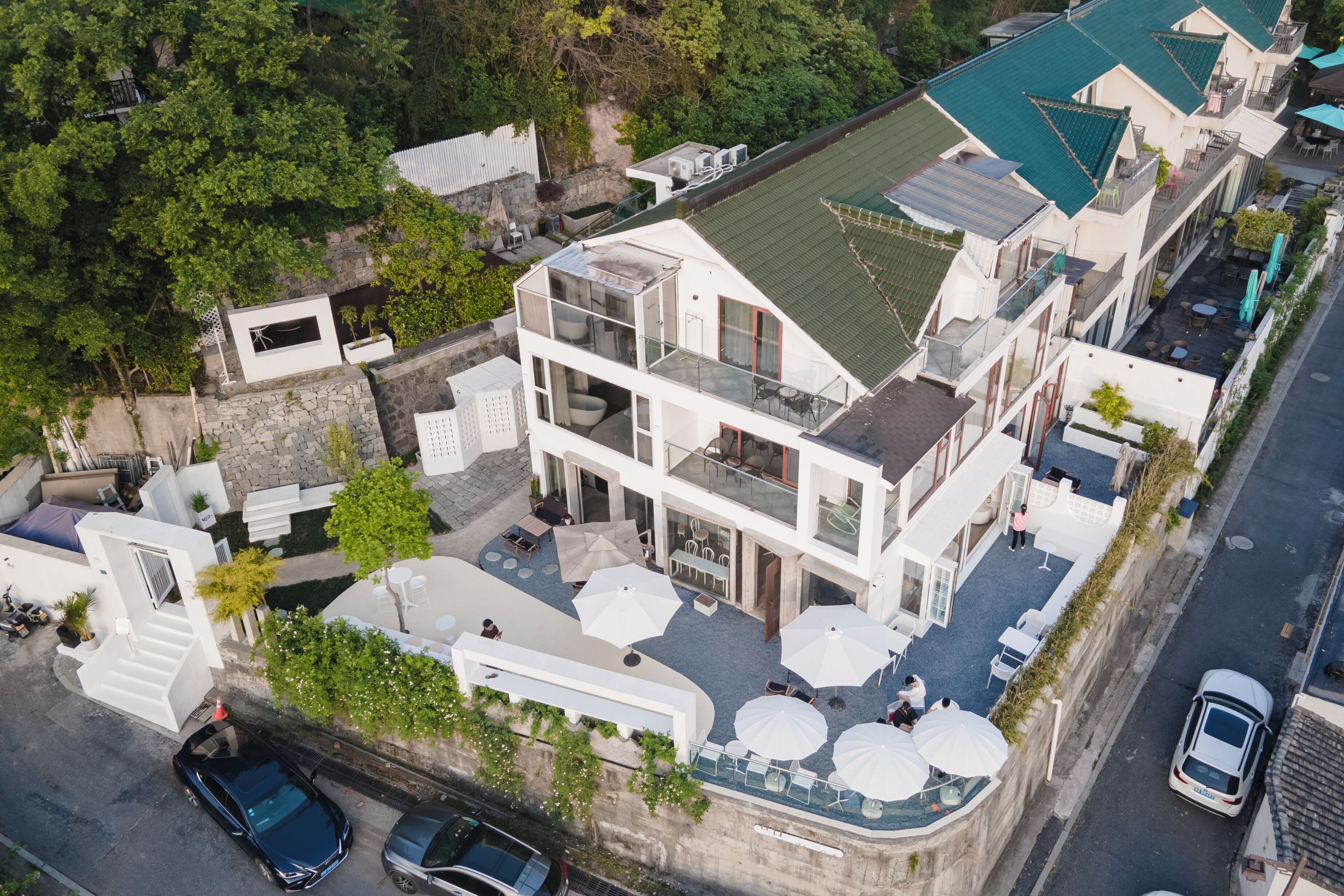 A multi-story building with a rooftop terrace, outdoor seating, and a swimming pool.