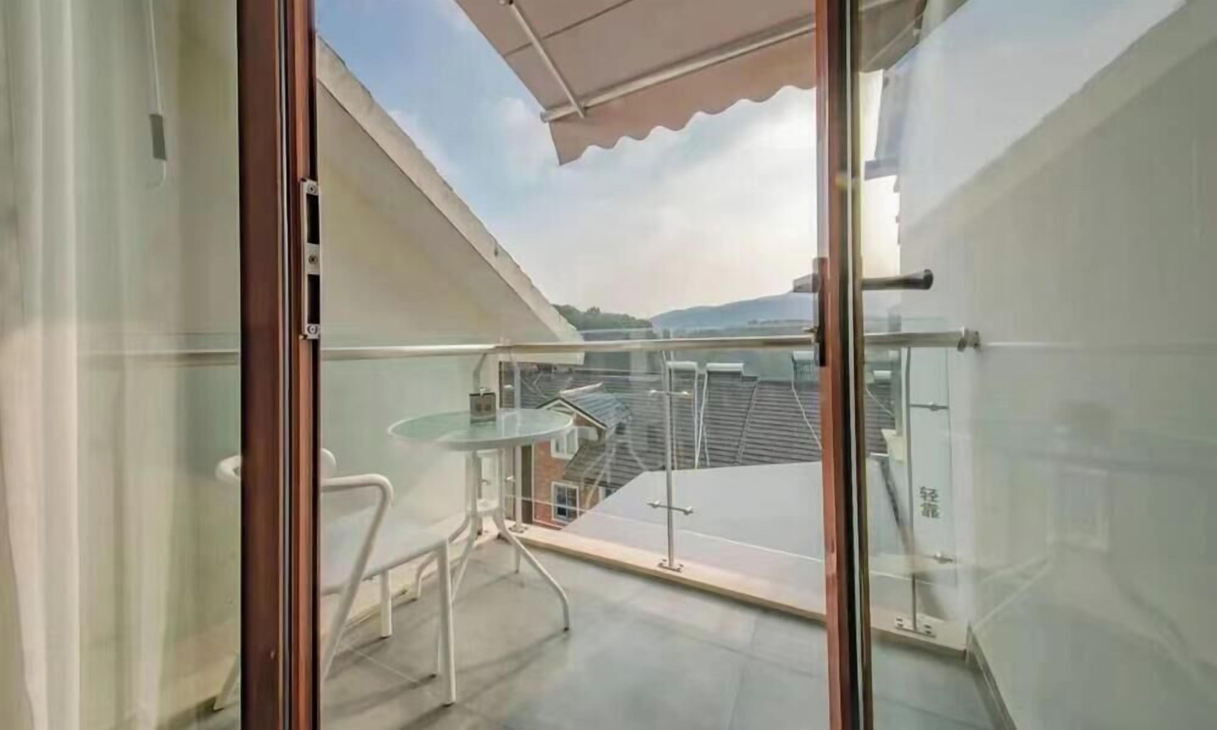 Un balcon avec une porte-fenêtre, une petite table et une chaise.