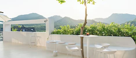 Una terraza en la azotea con zona de estar, un árbol y vistas a la montaña.