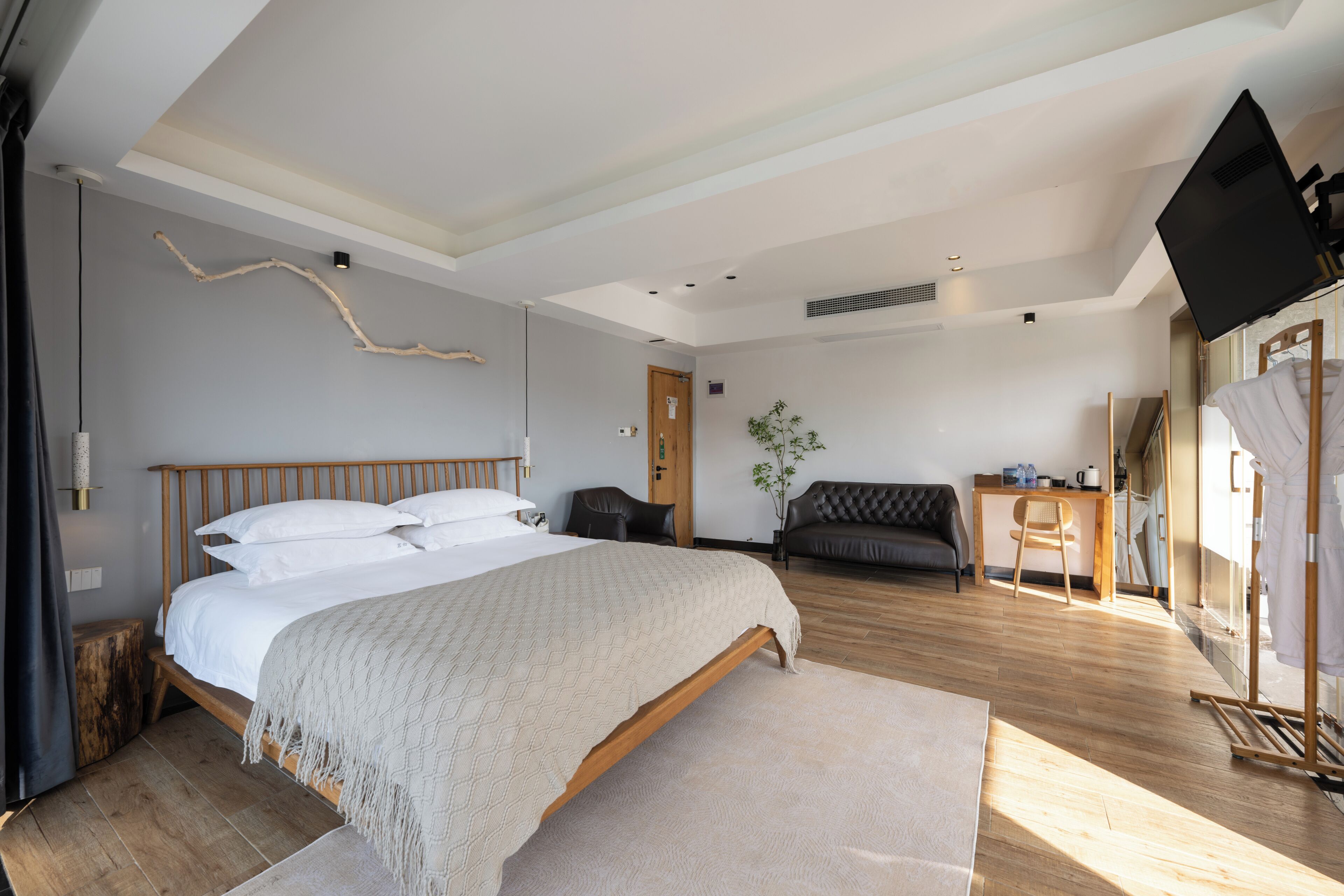 Un dormitorio moderno con una cama grande, un escritorio, una silla y una televisión.