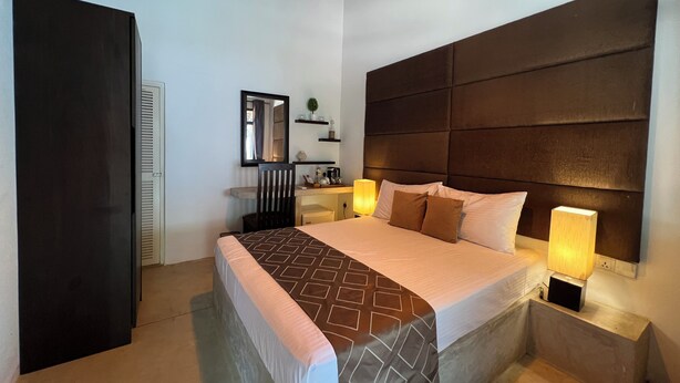 A hotel room with a bed, bedside lamps, a nightstand, a mirror, and a wardrobe. - Rankendiya Resort (Habarana)