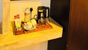 Un área de cocina con cafetera, una botella de agua y una bandeja con tazas y tetera.