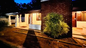 A modern building with a brick facade, a well-lit entrance, and a small bush in the foreground. - Rankendiya Resort (Habarana)