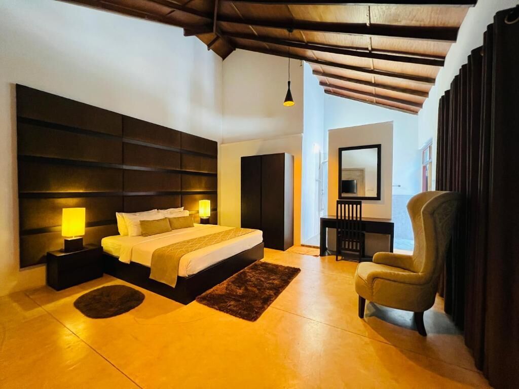 A bedroom with a large bed, bedside lamps, a chair, and a desk with a mirror.