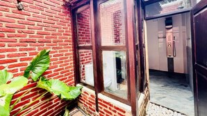 Pared de ladrillo rojo con una ventana, una puerta y un piso de baldosas.