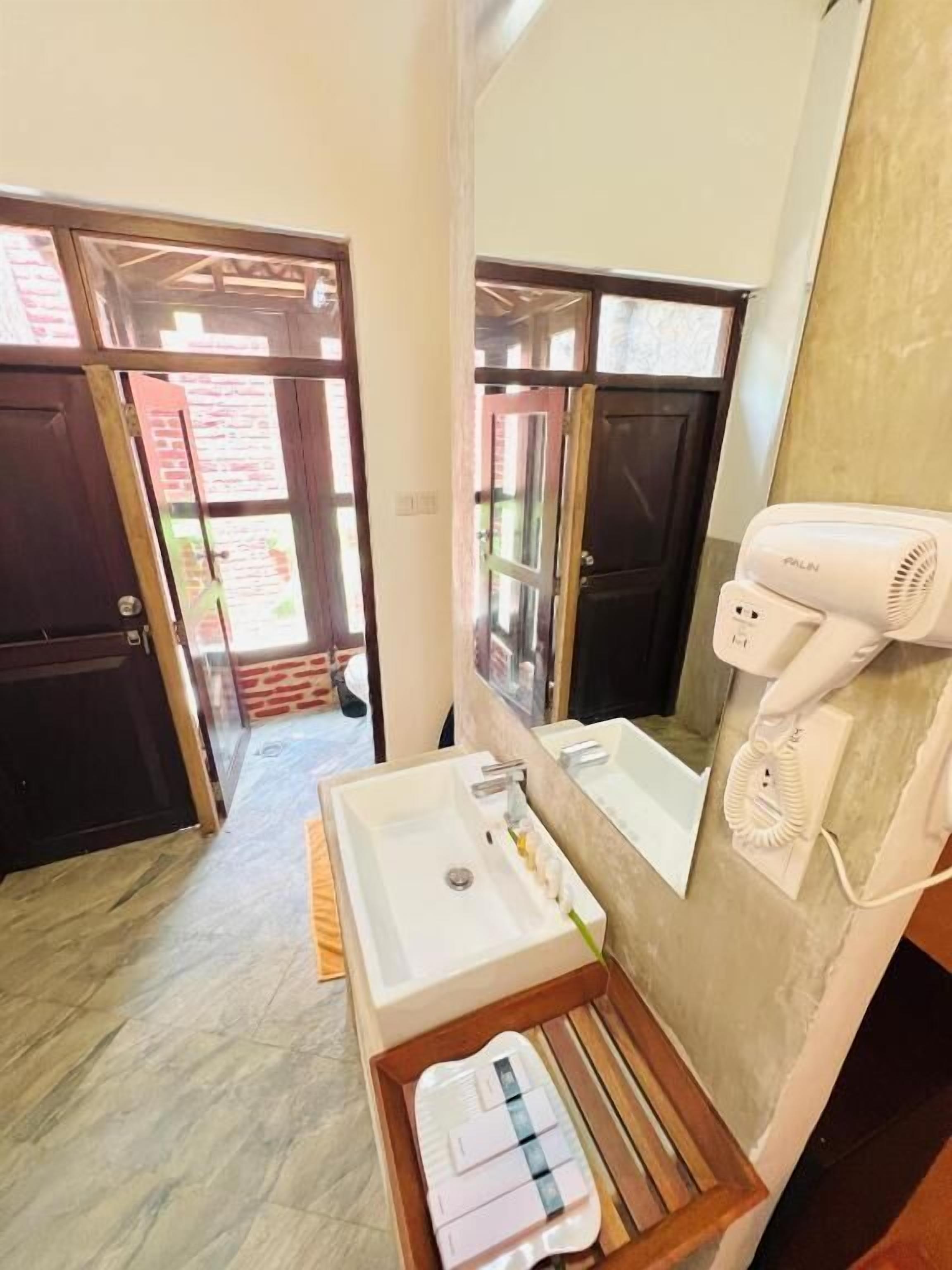 Un baño con lavamanos, espejo y secador de pelo.