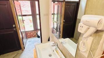 Un baño con lavamanos, espejo y secador de pelo.