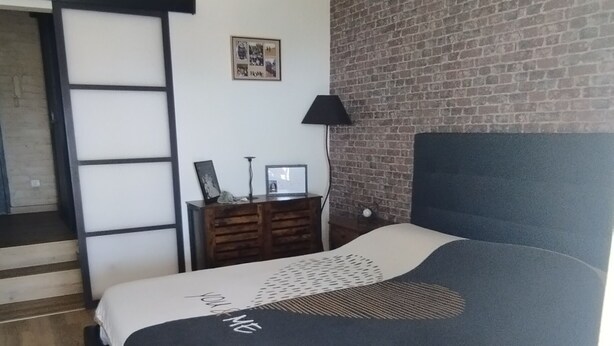 A bedroom with a bed, a ceiling fan, a brick wall, a wooden floor, and a door. - House with panoramic ocean views and a pool (MARSEILLE 15EME)