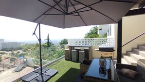 A balcony with a glass table, outdoor furniture, and a view of the cityscape. - House with panoramic ocean views and a pool (MARSEILLE 15EME)