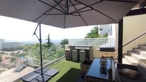 Ein Balkon mit Glastisch, Gartenmöbeln und Blick auf die Stadtlandschaft.