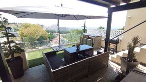 Ein Balkon mit Gartenmöbeln, einem großen Sonnenschirm und Blick auf die Stadtlandschaft.