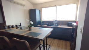 A modern kitchen with a dining table, chairs, a potted plant, and a window with a view. - House with panoramic ocean views and a pool (MARSEILLE 15EME)