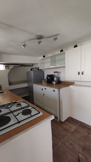 Eine Küche mit Gasherd, Kühlschrank, Mixer und weißen Schränken.