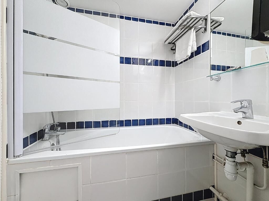 Une salle de bain avec une baignoire blanche, un lavabo et des murs recouverts de carreaux bleus.