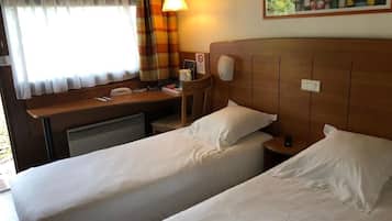 Une chambre d’hôtel avec deux lits, un bureau, une chaise, une lampe et un tableau au mur.