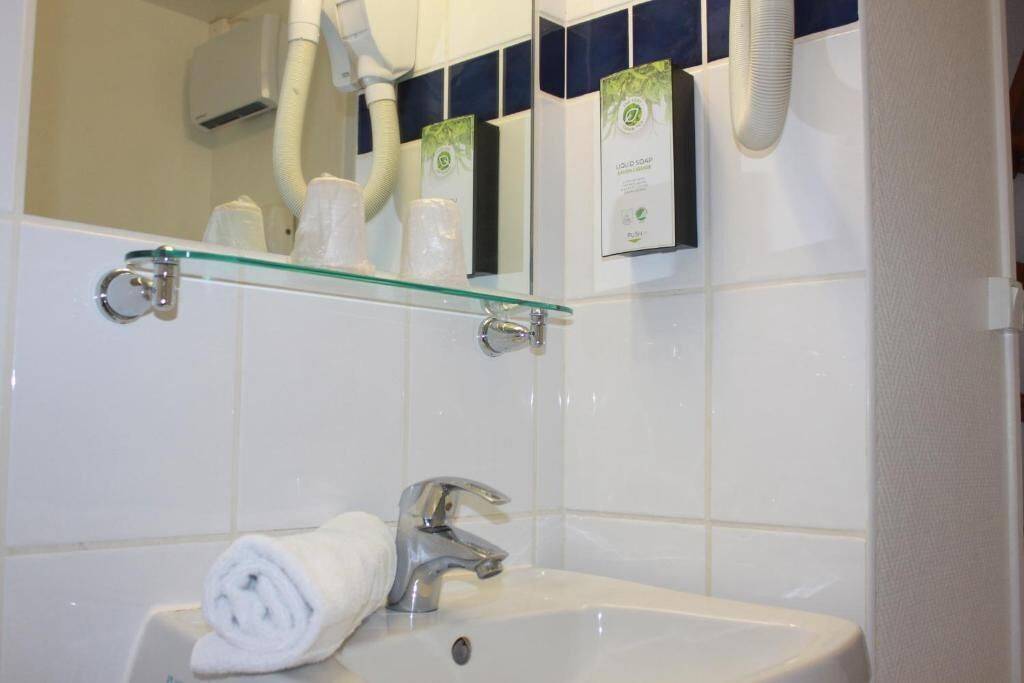 Et badeværelse med en glashylde med toiletartikler, en hvid vask og et håndklæde.