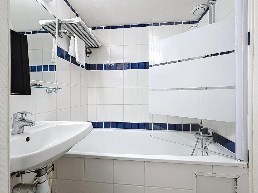 Un baño con un lavabo blanco, un espejo y una bañera.