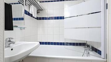 Un baño con un lavabo blanco, un espejo y una bañera.