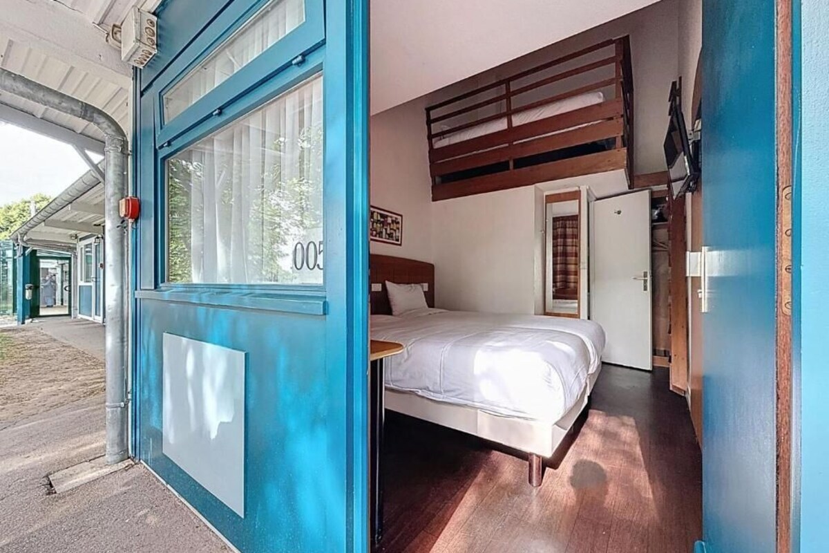 A room with a bunk bed, a small table, and a window with a view.