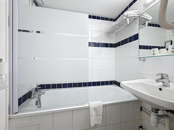 Une salle de bain avec une baignoire, un lavabo et un miroir.
