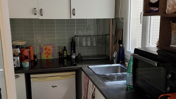 A compact kitchen with white cabinets, a built-in dishwasher, a microwave, and a window with a view.