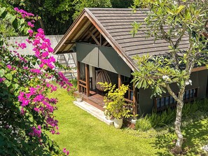 Ein Haus mit Satteldach, einer Veranda mit Schaukelstuhl und einem Garten mit rosa Blüten.