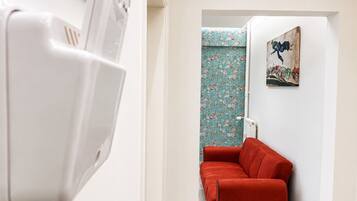 Ein Flur mit einem roten Sofa, einem Heizkörper und einer Wand mit floralem Wandpapier.