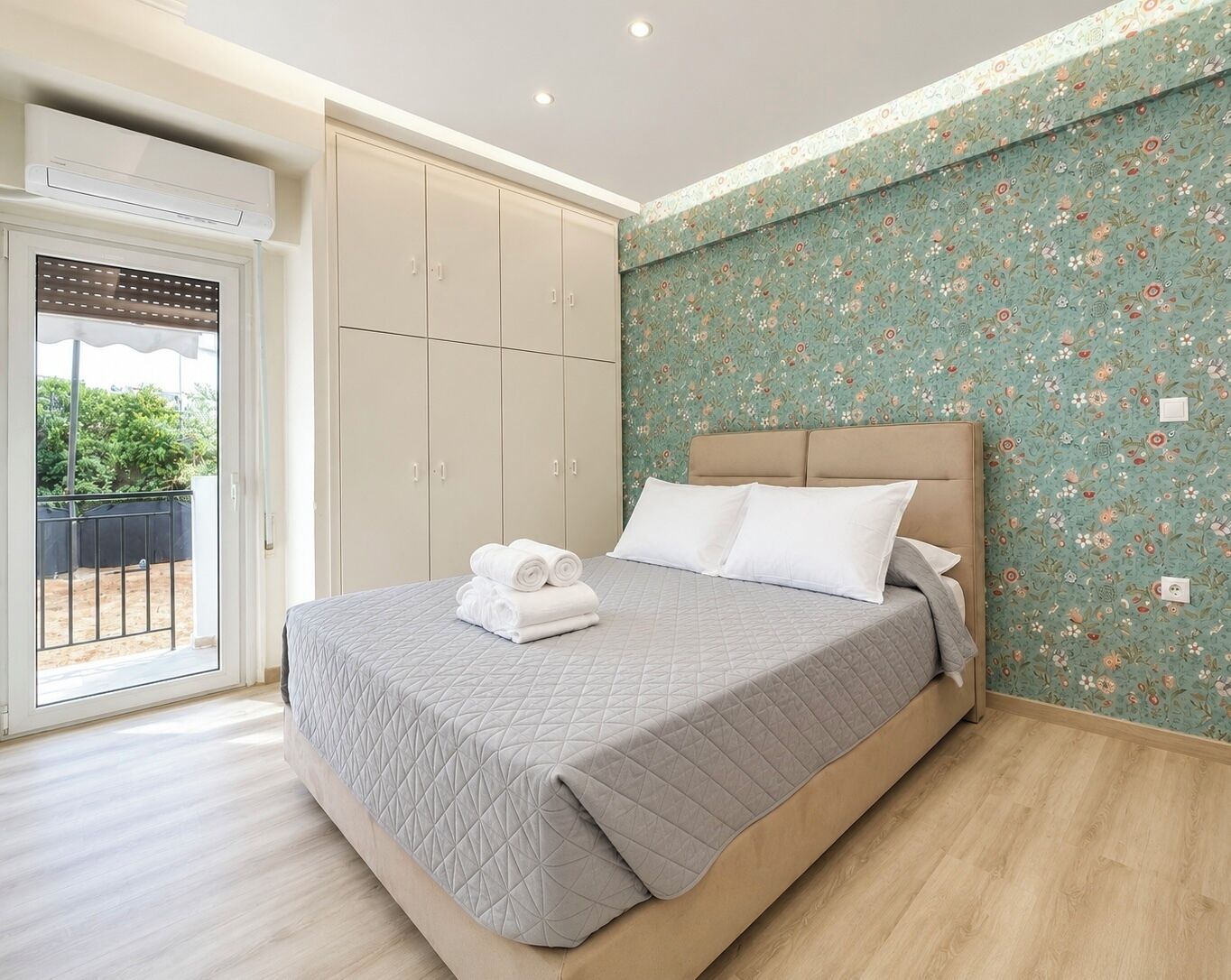 A bedroom with a bed, a wardrobe, and a balcony.