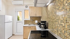 Une cuisine compacte équipée d’une cuisinière intégrée, d’une machine à café et d’un évier.