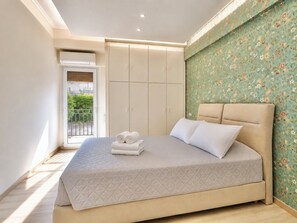 A bedroom with a bed, a wardrobe, and a balcony.