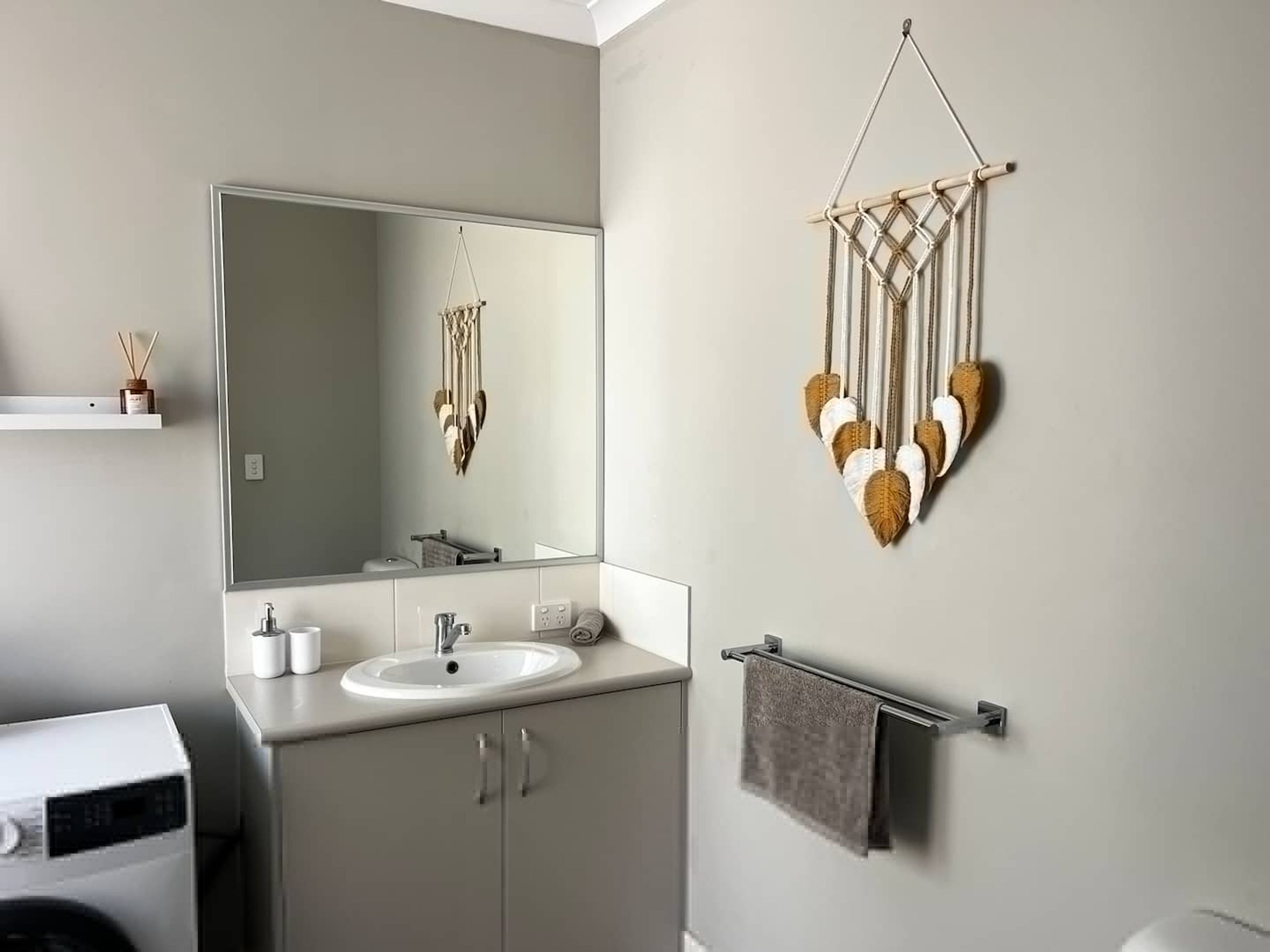Une salle de bain moderne avec un grand miroir, un lavabo et un porte-serviettes.