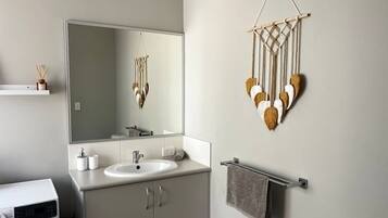 Une salle de bain moderne avec un grand miroir, un lavabo et un porte-serviettes.