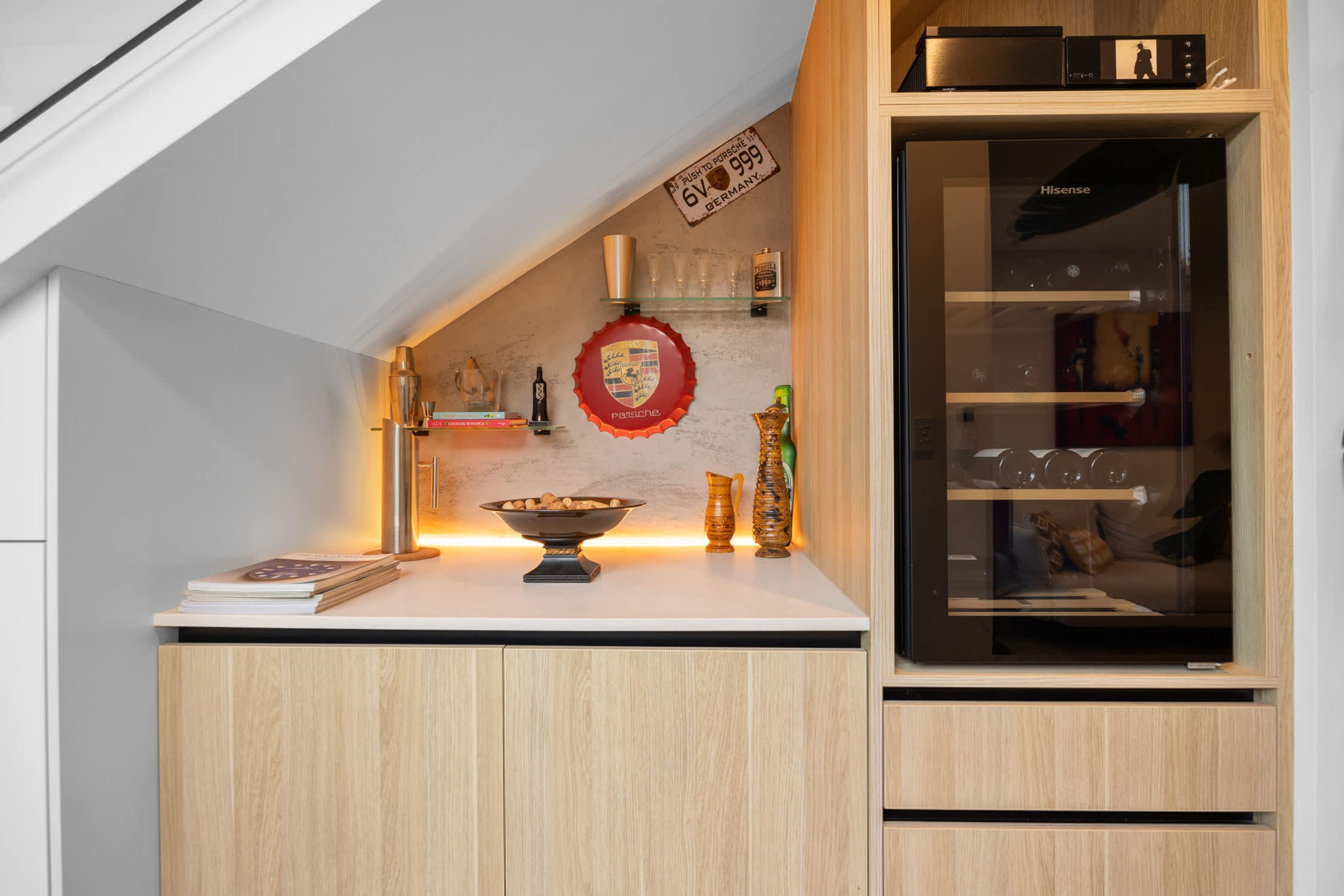 A kitchen with a wooden countertop, a glass cabinet, and a wall-mounted shelf with various items.