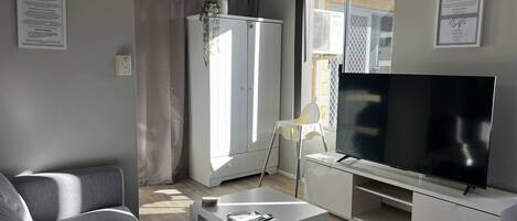 Una sala de estar moderna con un sofá, televisor y un mueble blanco.