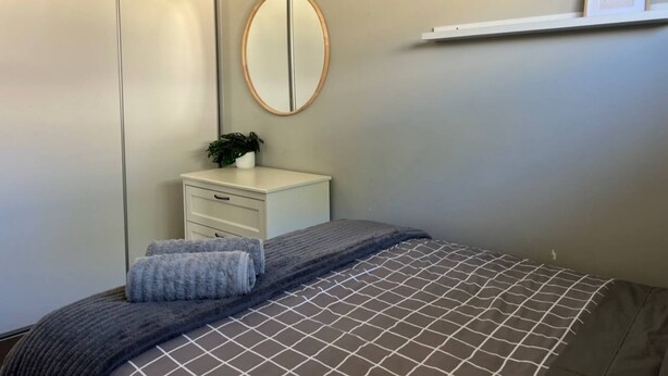 A bedroom with a bed, a dresser, a mirror, and a framed picture on the wall.