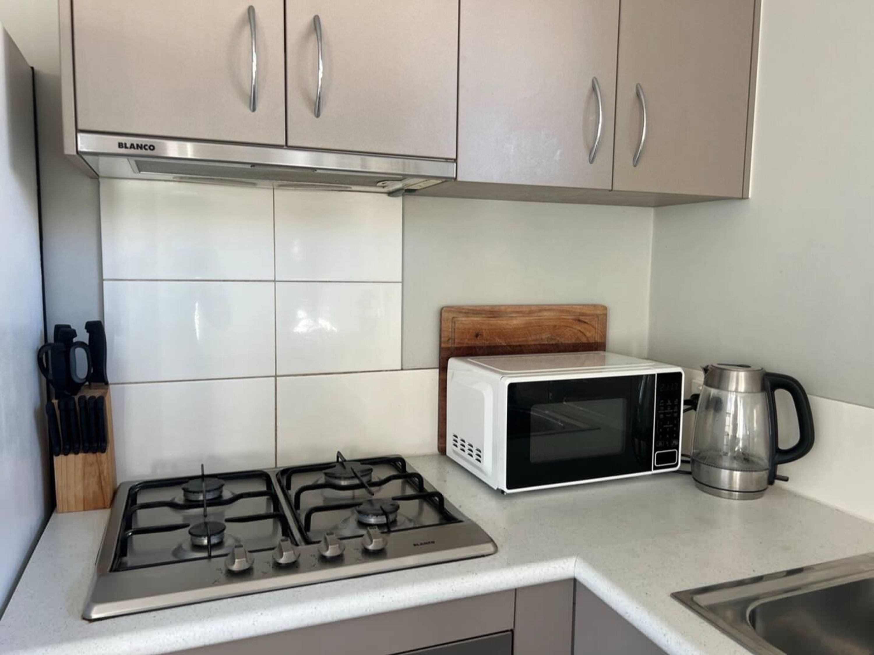 Une cuisine équipée d’une cuisinière à gaz, d’un four à micro-ondes et d’une machine à café.