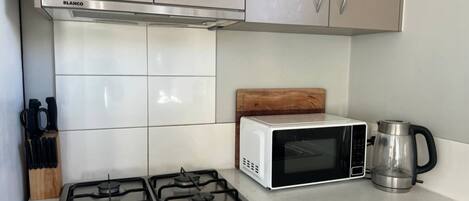 Une cuisine équipée d’une cuisinière à gaz, d’un four à micro-ondes et d’une machine à café.