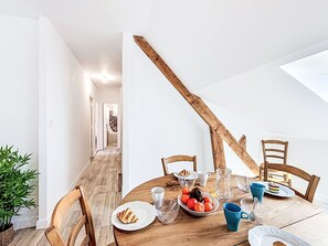 Ein Essbereich mit Holztisch, Stühlen und einer Obstschale.
