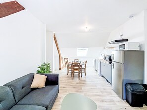 A modern kitchen with a dining area, a sofa, and a small table. - Gîte de la Grée by Interhome (Saint-Nolff)