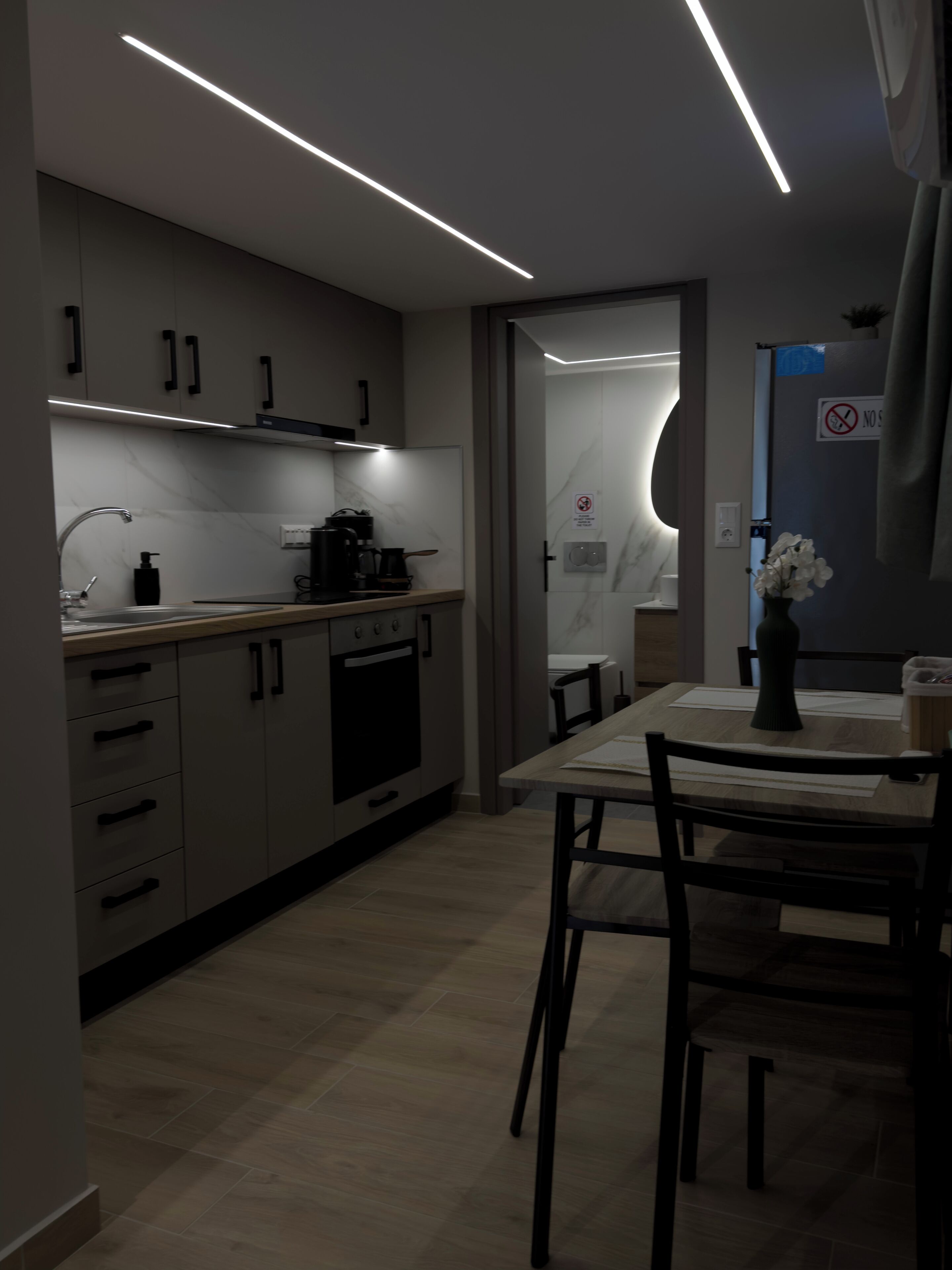 Una cocina moderna con comedor, que incluye horno empotrado, cafetera y mesa con sillas.