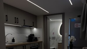 A modern kitchen with a dining area, featuring a built-in oven, a coffee machine, and a dining table with chairs. - Antonio Airport Loft-FREE AIRPORT SHUTLE (Markopoulo Mesogeas)