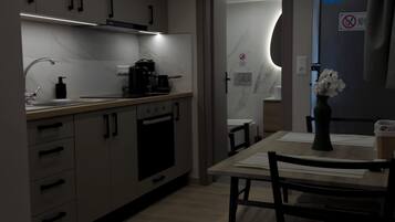 Una cocina moderna con comedor, que incluye horno empotrado, cafetera y mesa con sillas.
