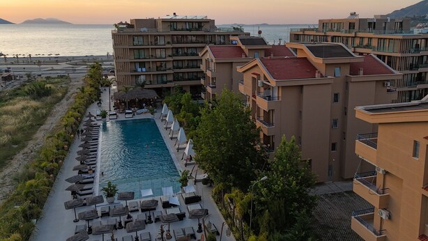 A hotel with a swimming pool, lounge chairs, and a view of the sea. - Golden Suite Palm Radhime (Orikum)