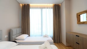 A hotel room with two beds, a wooden cabinet, and a large window with curtains. - Golden Suite Palm Radhime (Orikum)