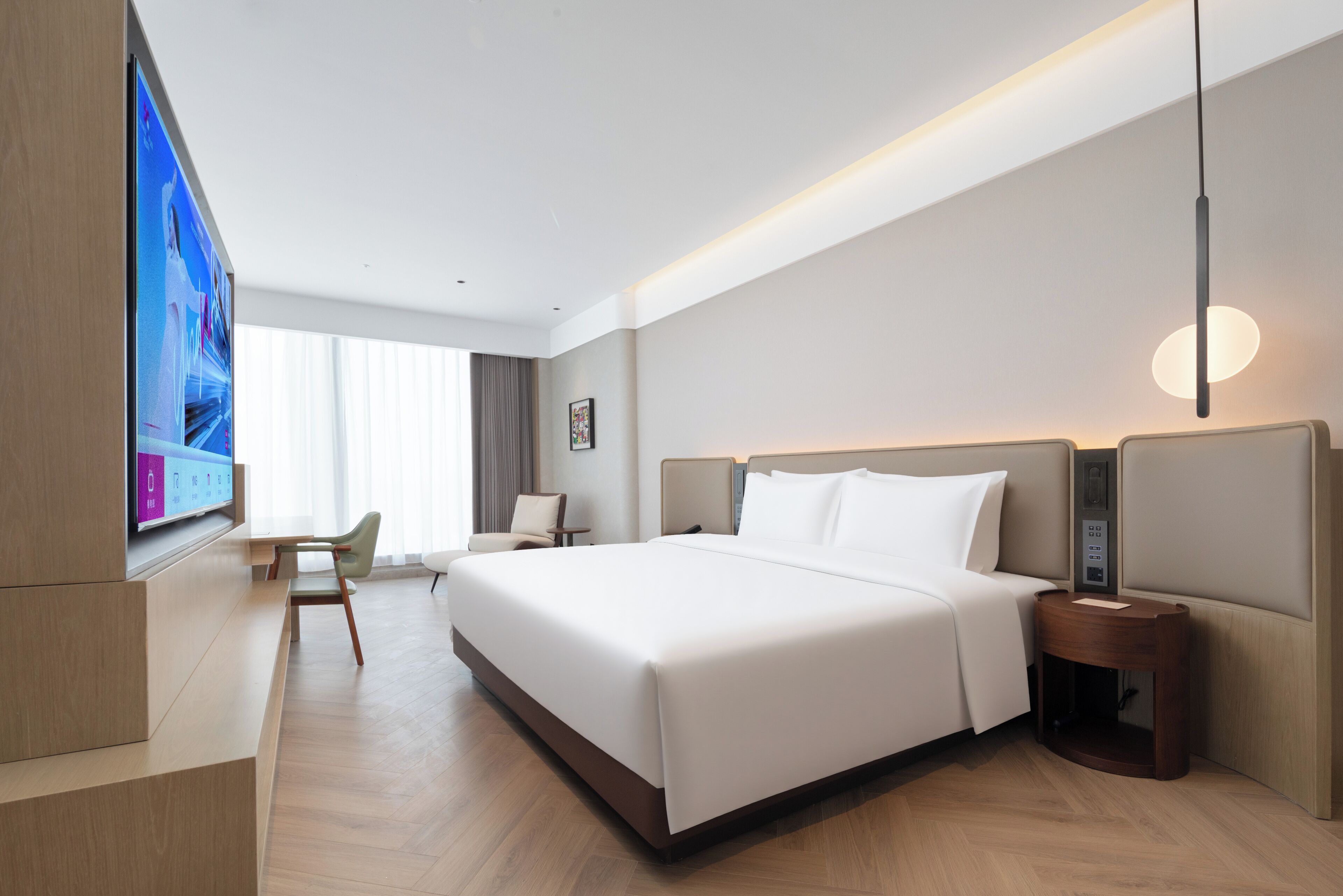 A modern hotel room with a large bed, a desk, and a television.
