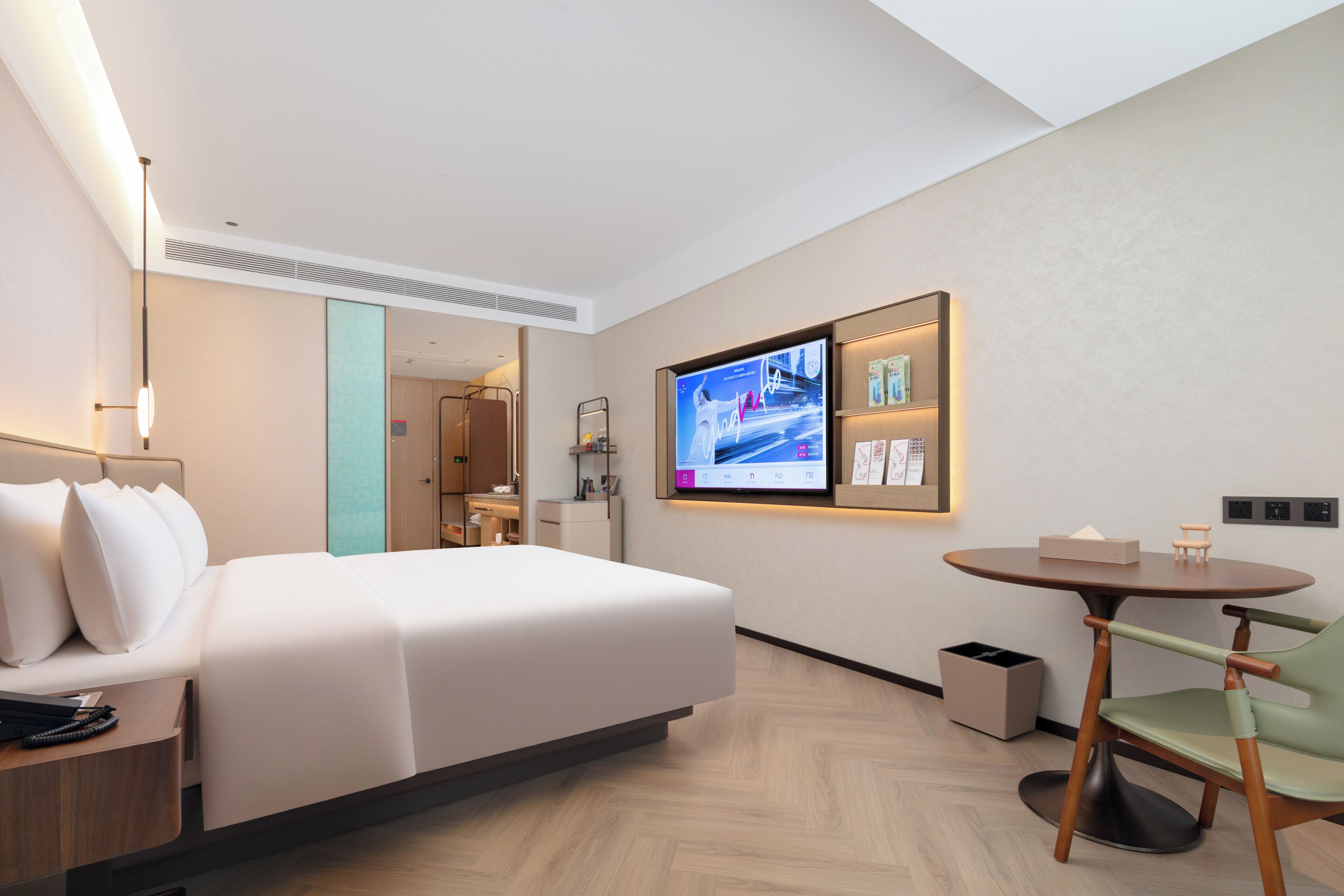 Habitación de hotel con cama, escritorio, silla, televisor y una mesita.