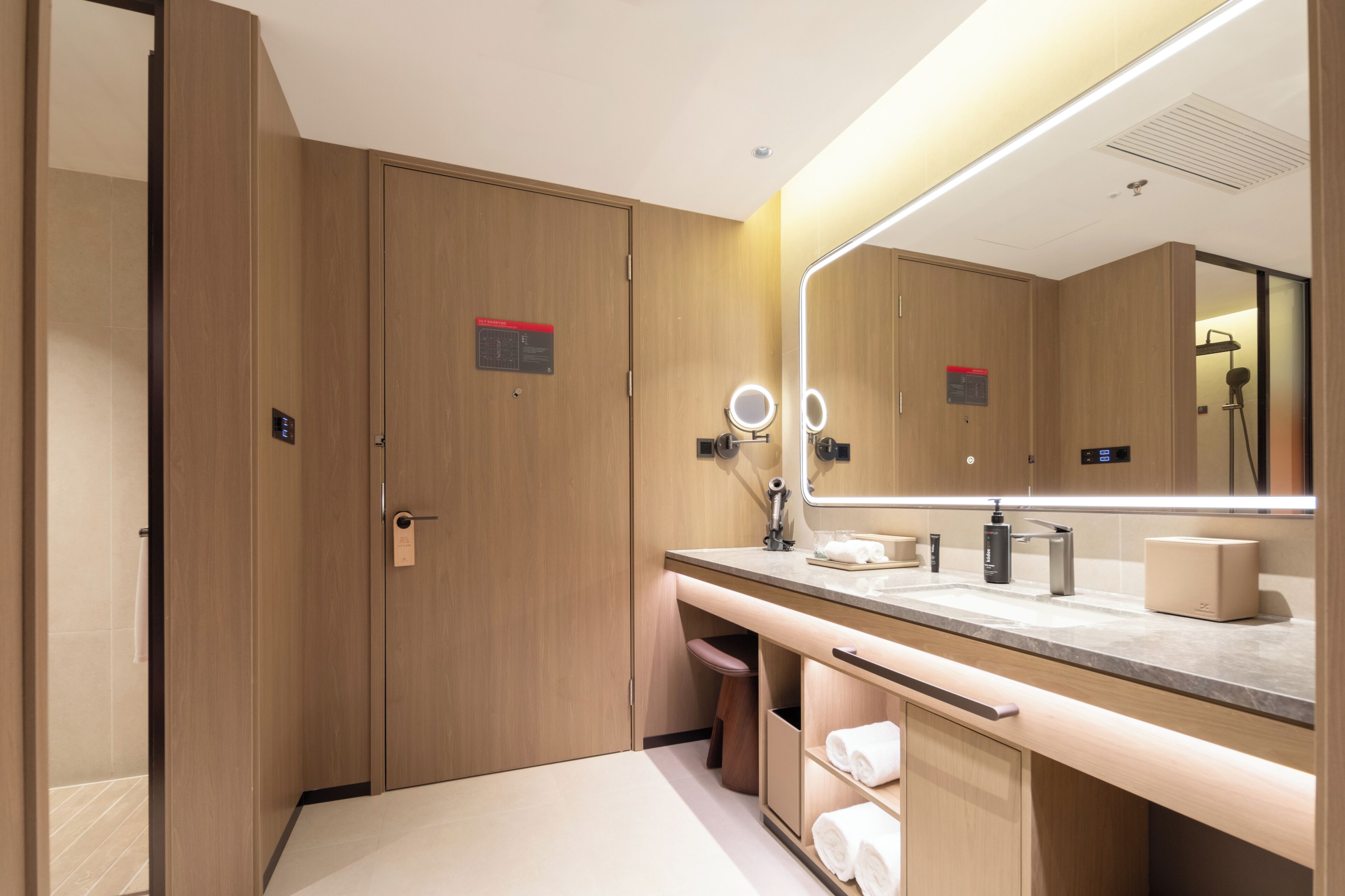 A modern bathroom with wooden cabinets, a vanity with a mirror, and a shower area.